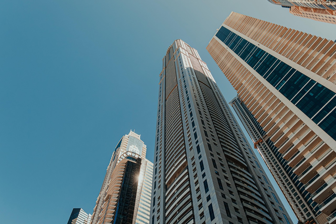 architectural design, architecture, business district, city, city center, cityscape, clear blue sky, corporate buildings, financial district, glass facades, high-rise buildings, high-rises, modern buildings, modern construction, modern metropolis, office buildings, residential towers, skyscrapers, tall towers, tower block, upward view, urban architecture, urban infrastructure, vertical architecture